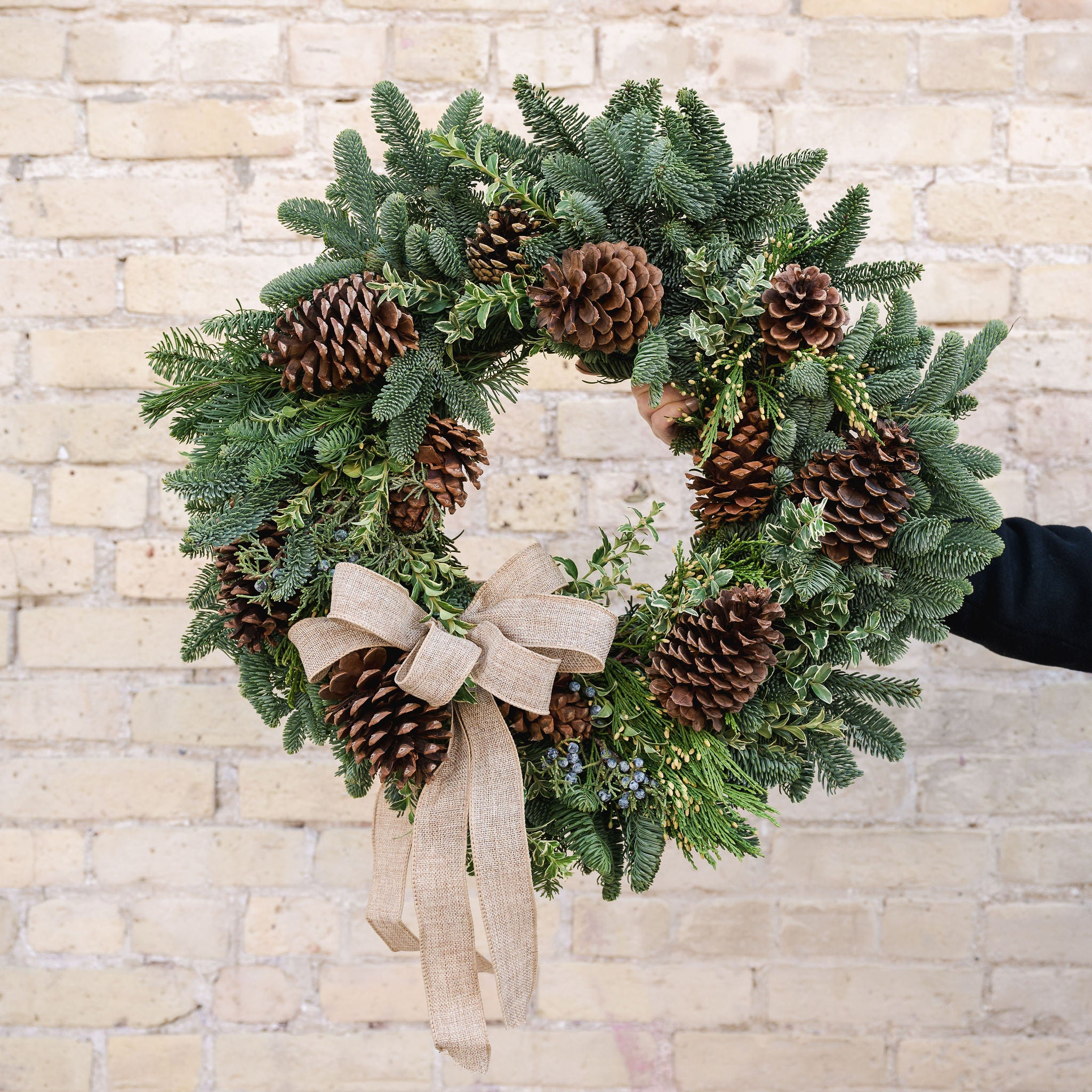 a wreath made of fragrant winter greens, natural pinecones and a burlap bow