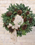 a wreath made of fragrant winter greens, natural pinecones and a burlap bow