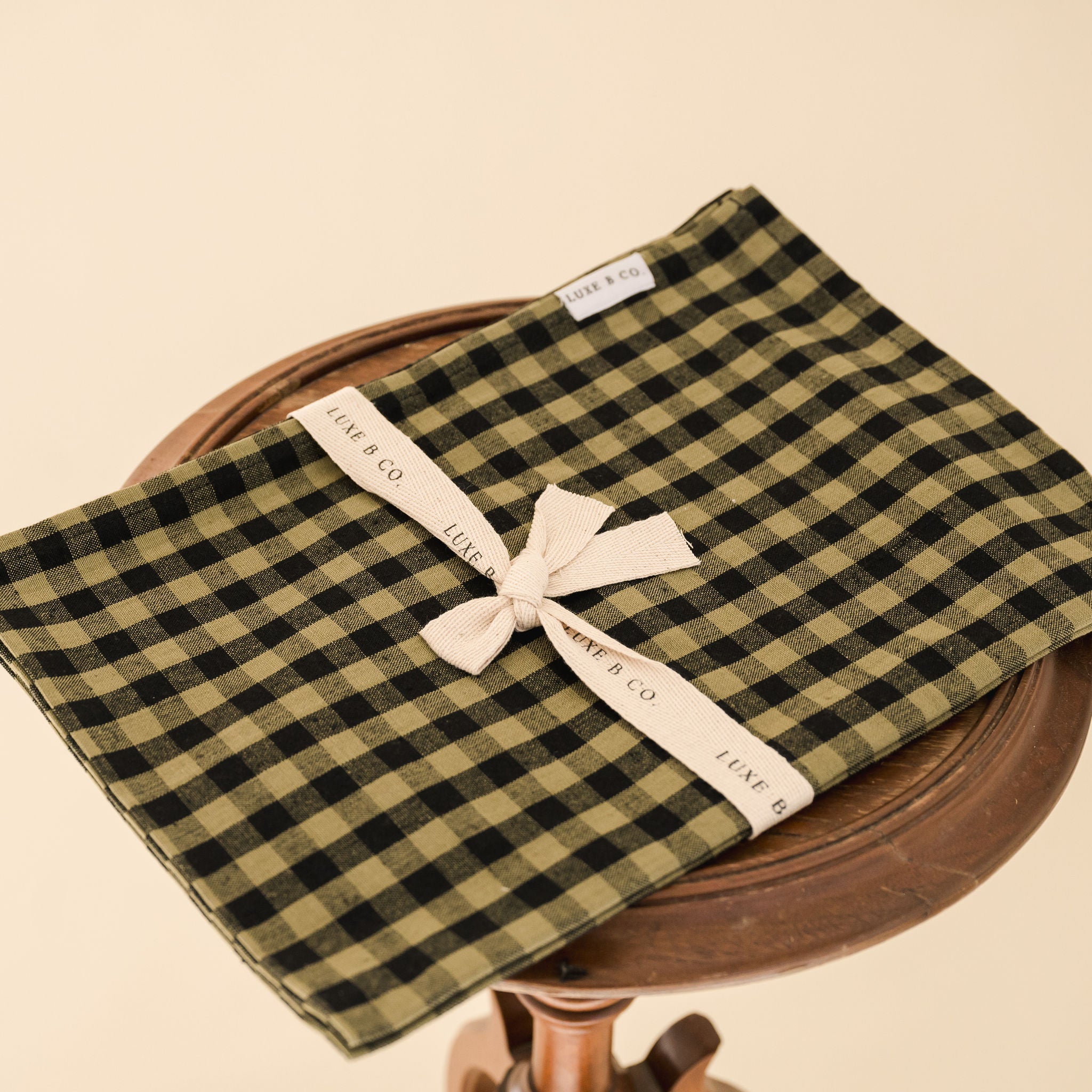 green and black gingham tea towel folded on a wooden stool