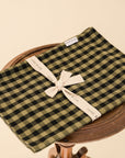 green and black gingham tea towel folded on a wooden stool