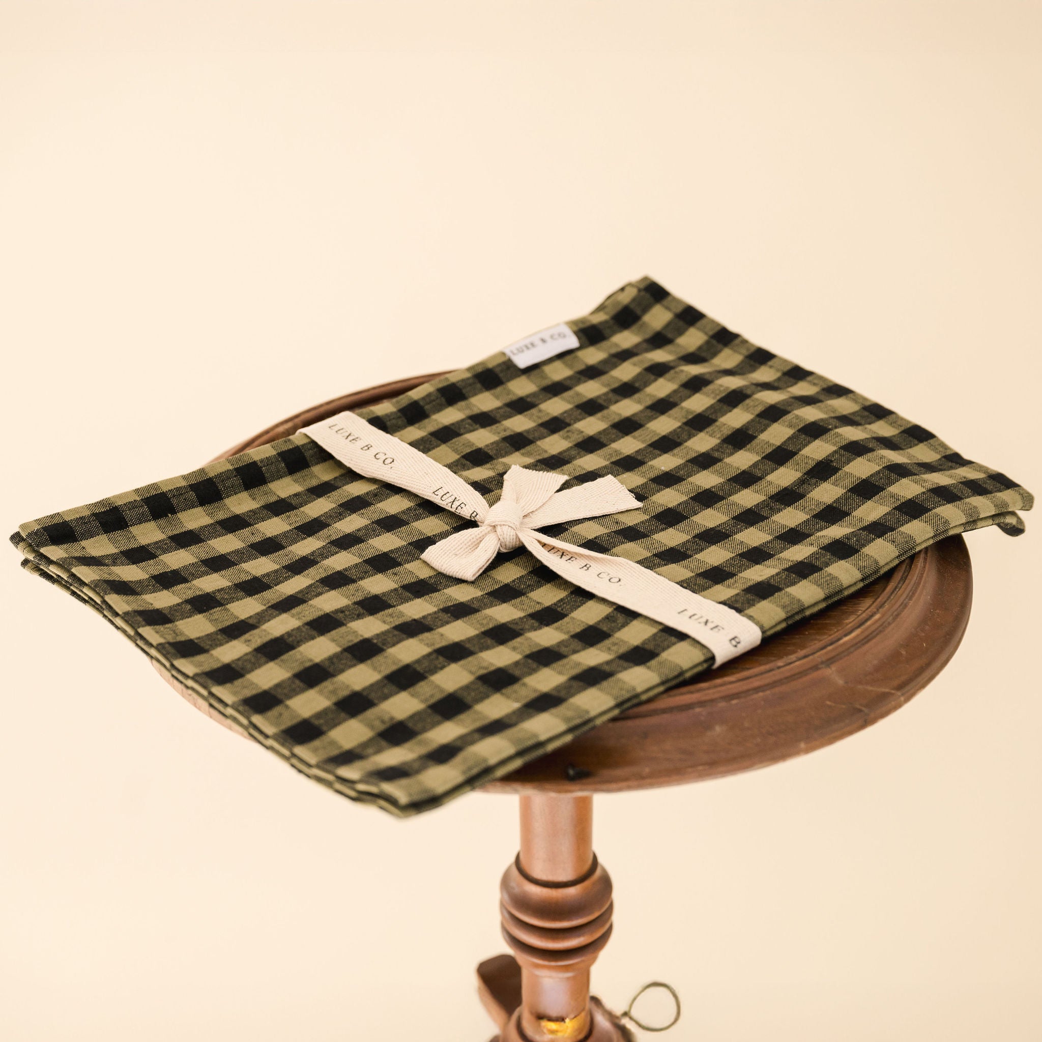 green and black gingham tea towel folded on a wooden stool