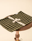 green and black gingham tea towel folded on a wooden stool