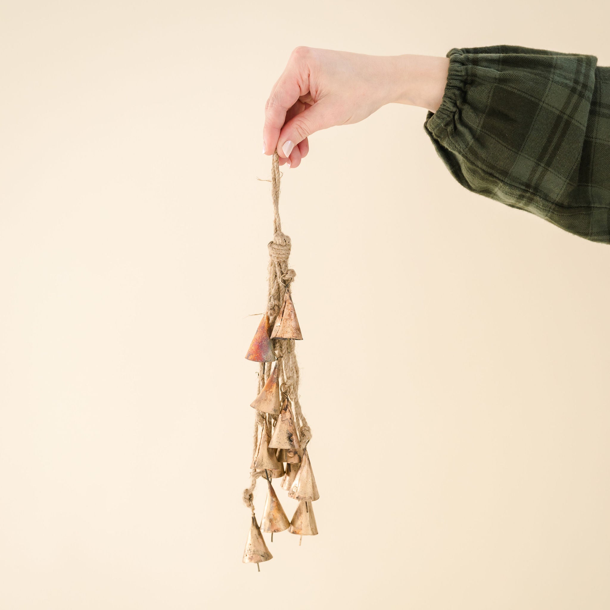 someone holding a gold bell cluster, tied with natural twine string