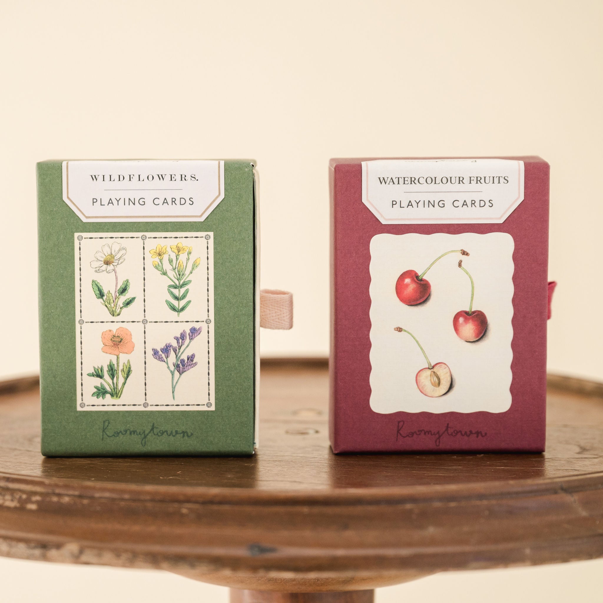 Wildflower and watercolour fruit playi8ng card boxes sitting on wooden sttol