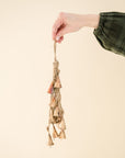 someone holding a gold bell cluster, tied with natural twine string