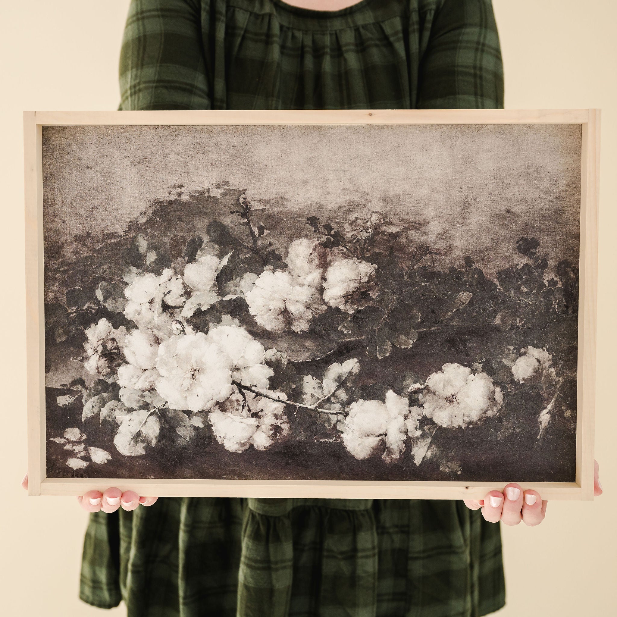 person in green dress holding framed print of white flowering branches