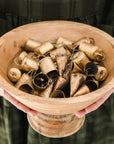 round wooden bowl filled with small gold bells help by someone in a green dress