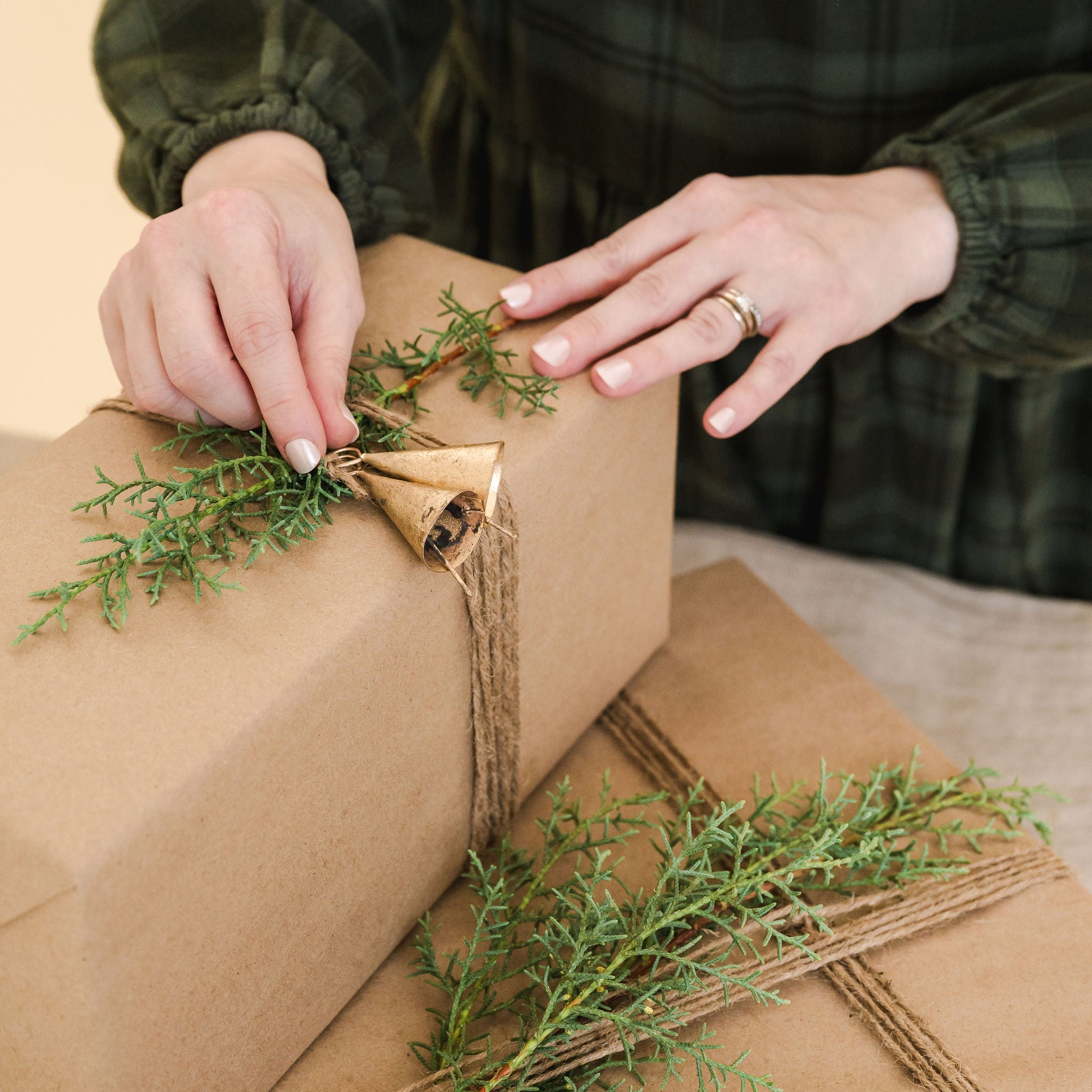 wrapped gift with winter greenery and two gold bells on top