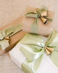 three gifts wrapped with sage ribbon and gold bells