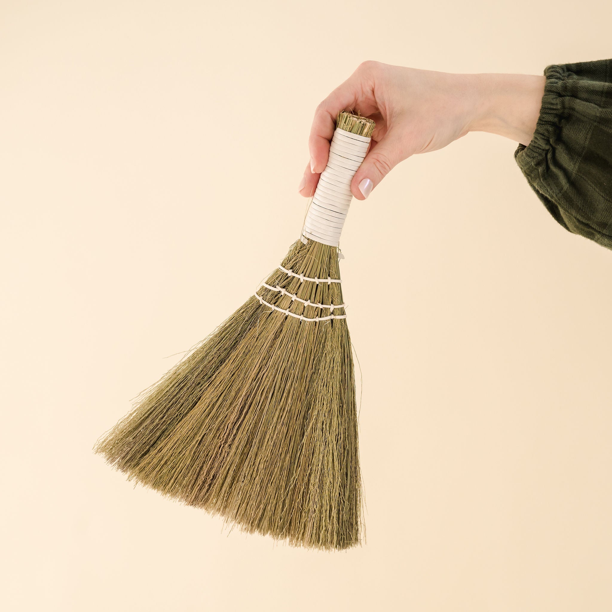 small broom held up against back drop